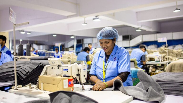 Pekerja konveksi mengoperasikan mesin jahit di pabrik tekstil untuk produksi seragam
